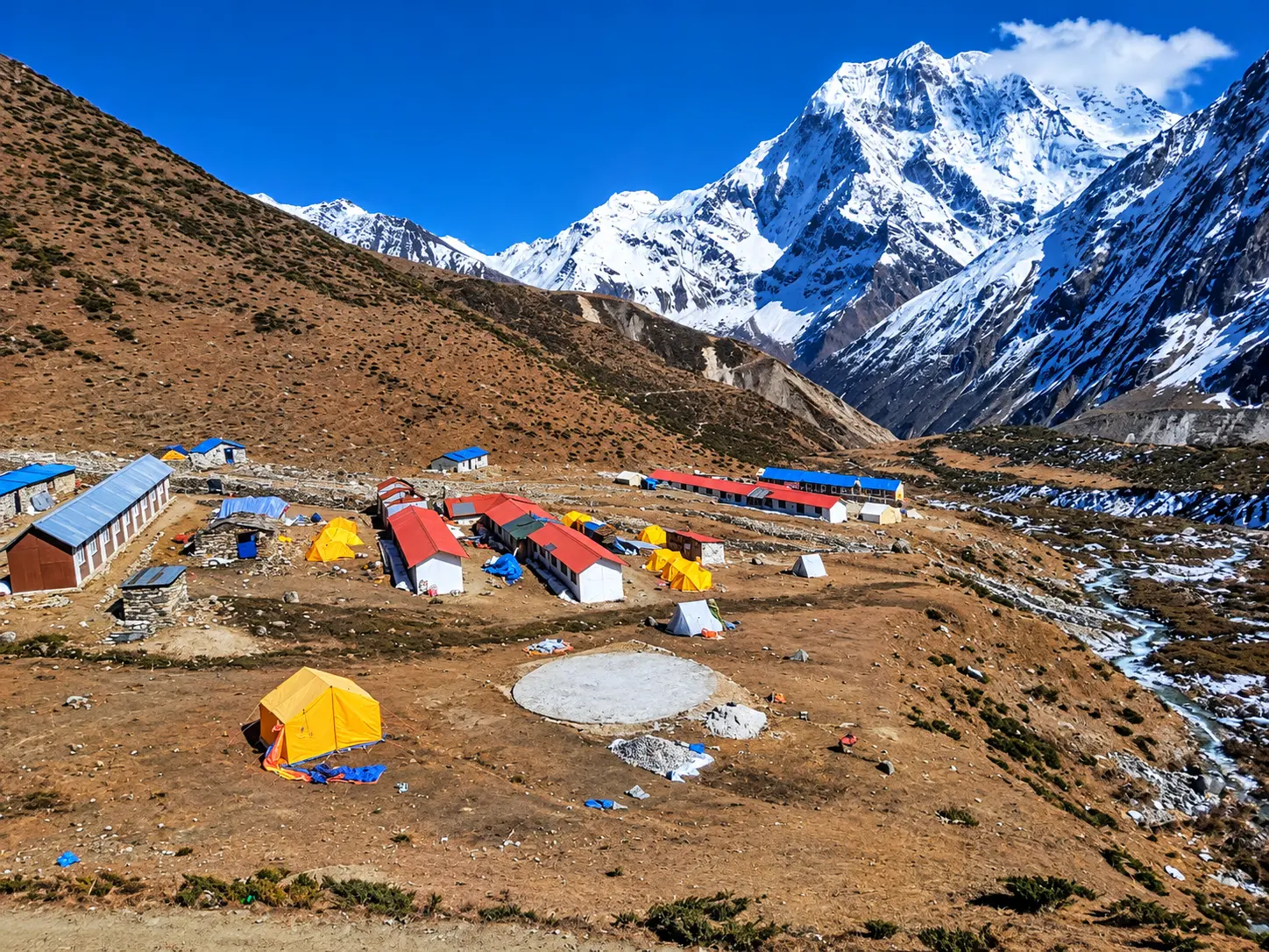 Snow-covered Himalayan peaks rising above a trekking settlement in Nepal